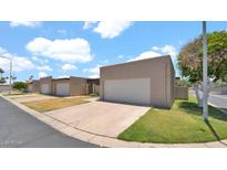Street view of townhomes featuring attached garages, well-maintained lawns, and desert landscaping at 3345 E University Dr # 47, Mesa, AZ 85213