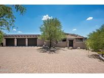 Charming home featuring a large driveway, mature tree, and three car garage under a beautiful blue sky at 41503 N 109Th Pl, Scottsdale, AZ 85262