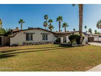Charming single-story home featuring a well-manicured lawn, desert landscaping, and numerous stately palm trees at 5333 E Sheena Dr, Scottsdale, AZ 85254
