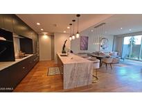 Modern kitchen boasts stone countertops, pendant lighting, stainless appliances, and open layout to the living room at 5455 E Lincoln Dr # 1004, Paradise Valley, AZ 85253