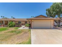Charming single-story home with a two-car garage, well-kept lawn and desert landscaping at 10236 N 105Th Dr, Sun City, AZ 85351