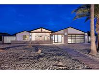 Beautiful modern home with desert landscaping, unique architectural details, and a sleek glass garage door at 11007 N 26Th St, Phoenix, AZ 85028