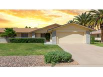 Charming single-story home featuring a two-car garage, desert landscaping, and lush green lawn at 12711 W Omega Dr, Sun City West, AZ 85375