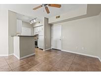 Bright living area with tile floors flowing into an efficient kitchen with white cabinets at 1701 E Colter St # 147, Phoenix, AZ 85016