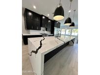 Modern kitchen boasts a large waterfall island with black accents and black cabinets at 5088 S Ponderosa Dr, Gilbert, AZ 85298