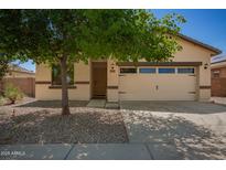 Charming single-story home featuring a two-car garage, desert landscaping, and mature shade tree at 7324 S 254Th Dr, Buckeye, AZ 85326