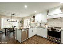Bright kitchen boasts white cabinets, granite countertops, stainless steel appliances, and wood flooring at 10284 E Mallow Cir, Scottsdale, AZ 85255