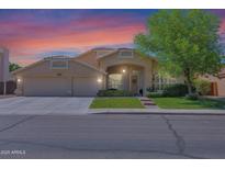 Charming home featuring a well-manicured lawn, mature tree, and a two-car garage, set against a beautiful sunset sky at 1420 W Raven Dr, Chandler, AZ 85286