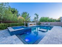 Inviting pool with integrated spa, in-pool seating, and stone fireplace feature at 22255 E Quintero Rd, Queen Creek, AZ 85142