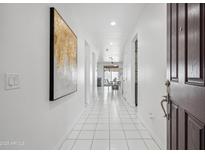 Inviting hallway with white tile flooring and modern art leading to an open dining area at 22341 N 100Th Ln, Peoria, AZ 85383