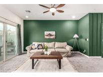 Comfortable living room features carpet, a ceiling fan, neutral paint, and a sliding glass door at 2256 W Laurie Ln, Phoenix, AZ 85021
