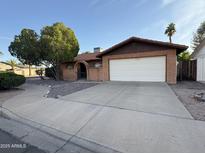 Charming single-story home featuring a brick facade, arched entryway, mature landscaping, and a spacious two-car garage at 2264 S Don Carlos --, Mesa, AZ 85202