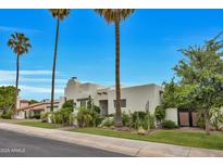 A charming white adobe home stands out with its lush landscaping, complemented by tall palm trees and blue skies at 3109 E Sierra Madre Way, Phoenix, AZ 85016