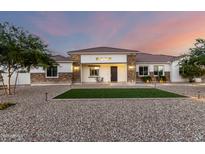 Charming single-story home featuring a decorative stone facade and tidy lawn with mature landscaping at 3911 N 197Th Ave, Buckeye, AZ 85396