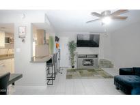 Inviting living room featuring modern tile flooring, a ceiling fan, and a gray entertainment center at 4255 N 68Th Dr, Phoenix, AZ 85033