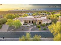 Expansive single-story home featuring a stone facade, desert landscaping, and mountain views at sunset at 6551 E Flat Iron Loop, Gold Canyon, AZ 85118