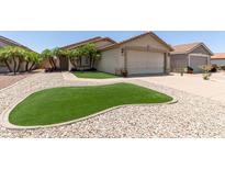 Charming single-story home featuring a beige exterior, a two car garage, and meticulous landscaping at 12425 W Willow Ave Ave, El Mirage, AZ 85335