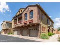 A three-story townhome boasts a stucco exterior, multi-car garages, and eye-catching stone accents at 1350 S Greenfield Rd # 1005, Mesa, AZ 85206