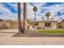 Charming single-story home boasting a well-maintained yard with lush landscaping and palm trees at 1887 E La Donna Dr, Tempe, AZ 85283