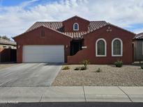 Charming single-story home with a terracotta-colored exterior, complemented by a well-manicured gravel front yard and a two-car garage at 36119 W Catalan St, Maricopa, AZ 85138