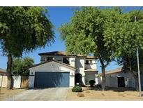 Charming two-story home with a blue garage door, mature trees, and well-maintained landscaping at 14922 N 172Nd Dr, Surprise, AZ 85388