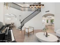 Bright living room featuring hardwood floors, modern furniture, and a grand staircase with a black railing at 4960 E Colonial Dr, Chandler, AZ 85249