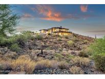 Expansive custom home on a hillside featuring multiple patios, stone accents, and breathtaking views during sunset at 16119 N Desert Fox Pkwy, Fountain Hills, AZ 85268
