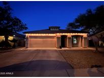 Charming single-story home featuring a two-car garage and nicely landscaped front yard at night at 24229 W Tonto St, Buckeye, AZ 85326