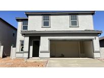 Two-story home featuring a wide two car garage and a gray stucco facade, complemented by a well manicured lawn at 29775 N Oak Dr, Florence, AZ 85132