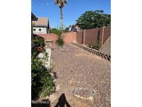 View of the desert landscaped backyard surrounded by a brick fence and some shrubbery at 9934 E Empress Ave, Mesa, AZ 85208