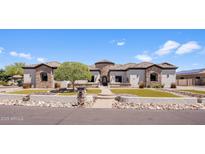 Stunning single-story home featuring manicured lawn, stone accents and tile roof, and a circular turret entrance at 18036 W San Miguel Ave, Litchfield Park, AZ 85340