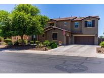 Two-story stucco home featuring a three-car garage, mature landscaping, and a tiled roof at 19427 W Colter St, Litchfield Park, AZ 85340