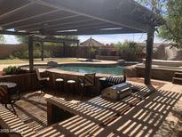 Relaxing backyard pool area with a pergola, built in barbeque, bar and plenty of seating at 35743 W Cartegna Ln, Maricopa, AZ 85138
