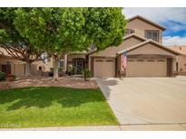 Charming two-story home with a well-manicured lawn, mature tree and a three car garage at 6862 W Honeysuckle Dr, Peoria, AZ 85383