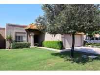Charming home with a well-maintained lawn, lush green shrubs, and an attached two-car garage at 9419 E Riviera Dr, Scottsdale, AZ 85260
