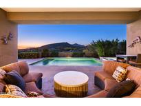 Inviting covered patio with plush seating overlooking a sparkling pool and captivating mountain views at 9894 E Miramonte Dr, Scottsdale, AZ 85262