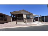 Charming home featuring a covered porch and carport, surrounded by easy-care desert landscaping at 9333 E University Dr # 57, Mesa, AZ 85207