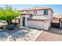 Inviting two-story home featuring a well-manicured front yard, charming architectural details, and an attached two-car garage at 9735 W Kirby Ave, Tolleson, AZ 85353