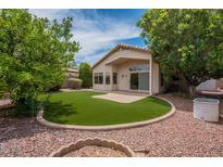 Well-manicured backyard featuring artificial grass, mature trees, and a quaint patio area at 10722 W Irma Ln, Peoria, AZ 85373