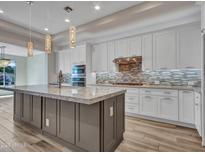 Modern kitchen features a large island, stainless steel appliances, white cabinets, and stylish lighting at 16881 W Merrell St, Goodyear, AZ 85395