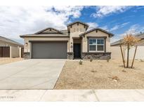 Charming home features a two-car garage, neutral stucco, and stone accents with a well-maintained landscape at 24047 W Cocopah St, Buckeye, AZ 85326