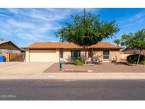 Charming single-story home featuring a well-maintained front yard, mature tree, and a two-car garage at 12241 N 49Th Ave, Glendale, AZ 85304