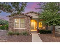 Charming single-story home with stone accents, a covered porch, and manicured landscaping at 15488 W Aster Dr, Surprise, AZ 85379