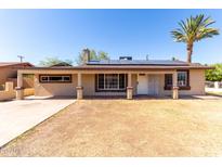 Inviting single-story home with a desert landscape, solar panels, and a mature palm tree at 2064 W 2Nd St, Mesa, AZ 85201