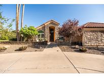 Charming stone home with a unique arched entryway, mature trees, and a well-manicured lawn at 2107 E Park Ave, Gilbert, AZ 85234