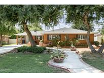Charming brick home with lush landscaping, mature trees, and a welcoming walkway at 5808 N 18Th Pl, Phoenix, AZ 85016