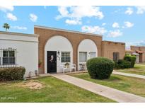 Charming single-story brick home featuring a well-manicured lawn and inviting front entry at 614 N Pioneer Cir, Mesa, AZ 85203