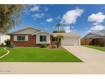 Charming single-Gathering home featuring a red brick exterior, green lawn, and a paved driveway leading to an attached garage at 8301 E Indianola Ave, Scottsdale, AZ 85251