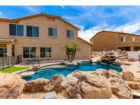 Backyard with a custom pool featuring a rock waterfall and slide, plus a small island with palm trees at 84 E Joseph Way, Gilbert, AZ 85295