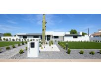 Stunning modern home featuring desert landscaping with a tall saguaro cactus and a well-manicured lawn at 11601 N 64Th Pl, Scottsdale, AZ 85254